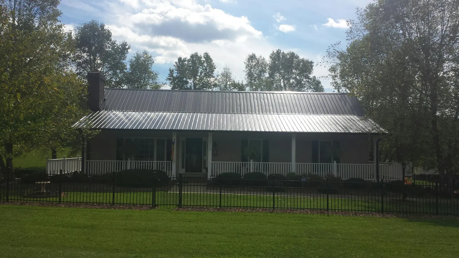 Gray metal roof on a brick ranch with a full width front porch — Gutter Guard Installation work by our crew in Moosic