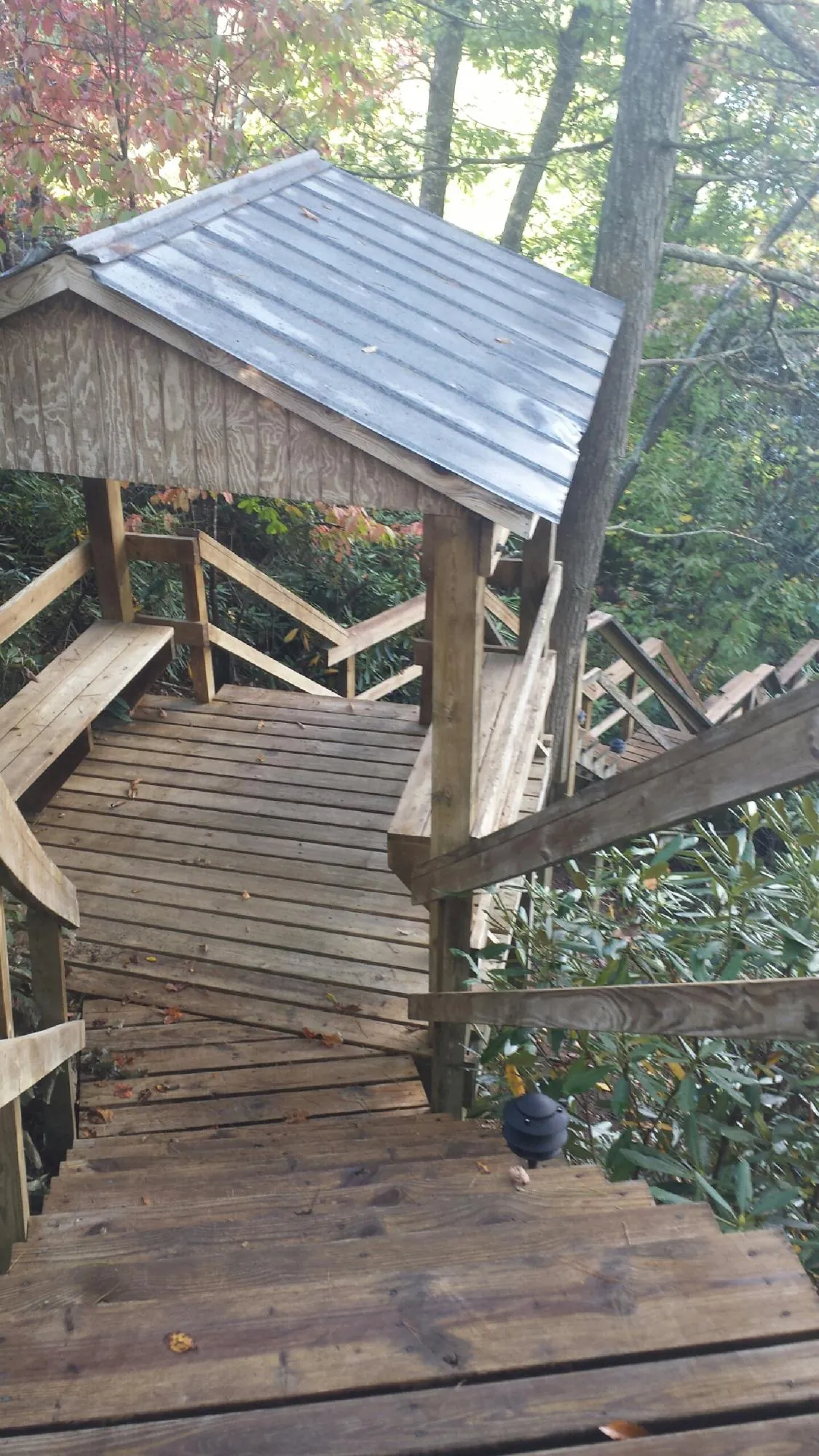 Metal roofed shelter over wooden steps on a wooded walkway — Skylight Repair & Installation work by our crew in Moosic