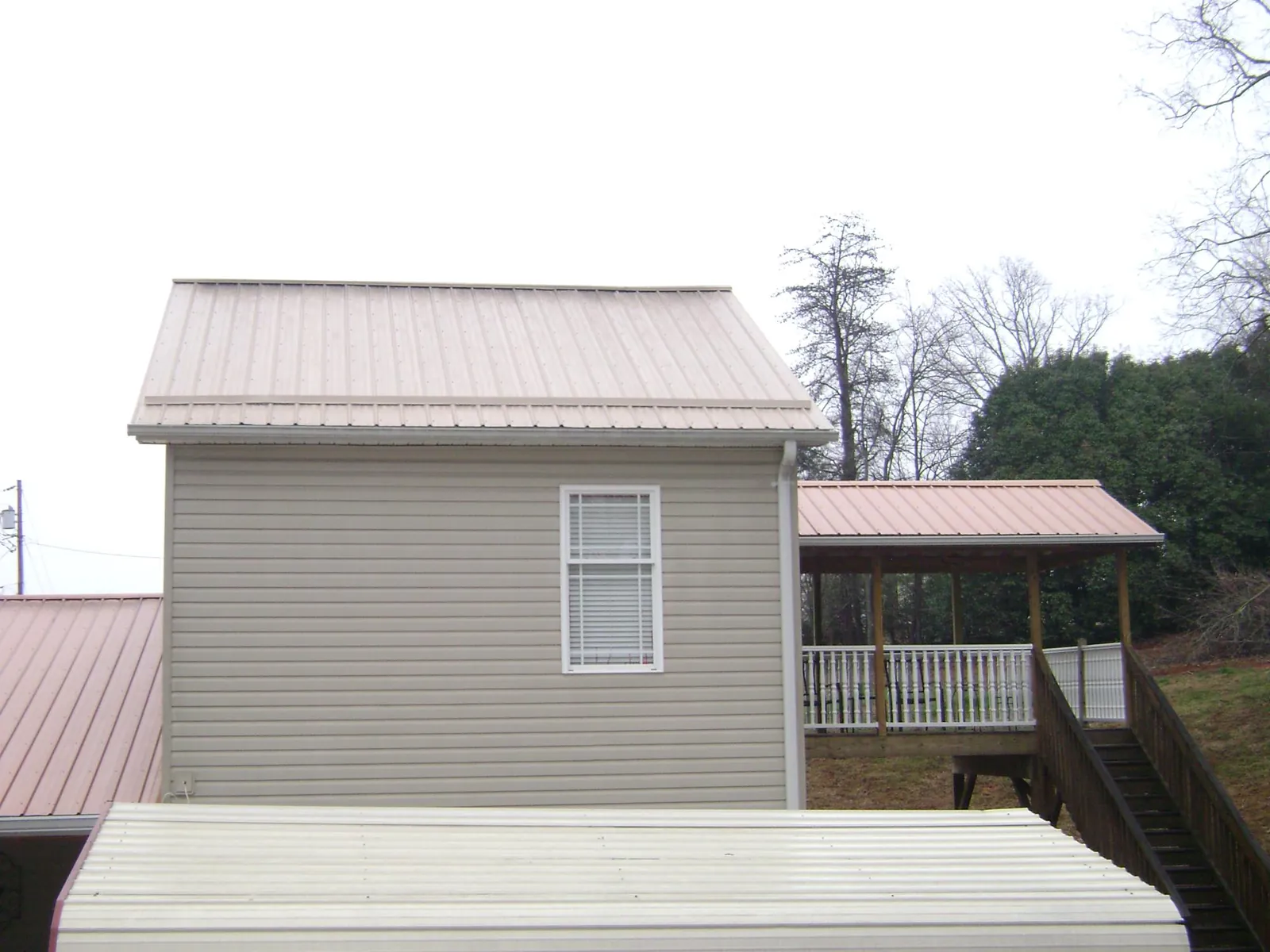 Tan metal roofs on a two story addition and attached porch, from a Roof Replacement job in Moosic