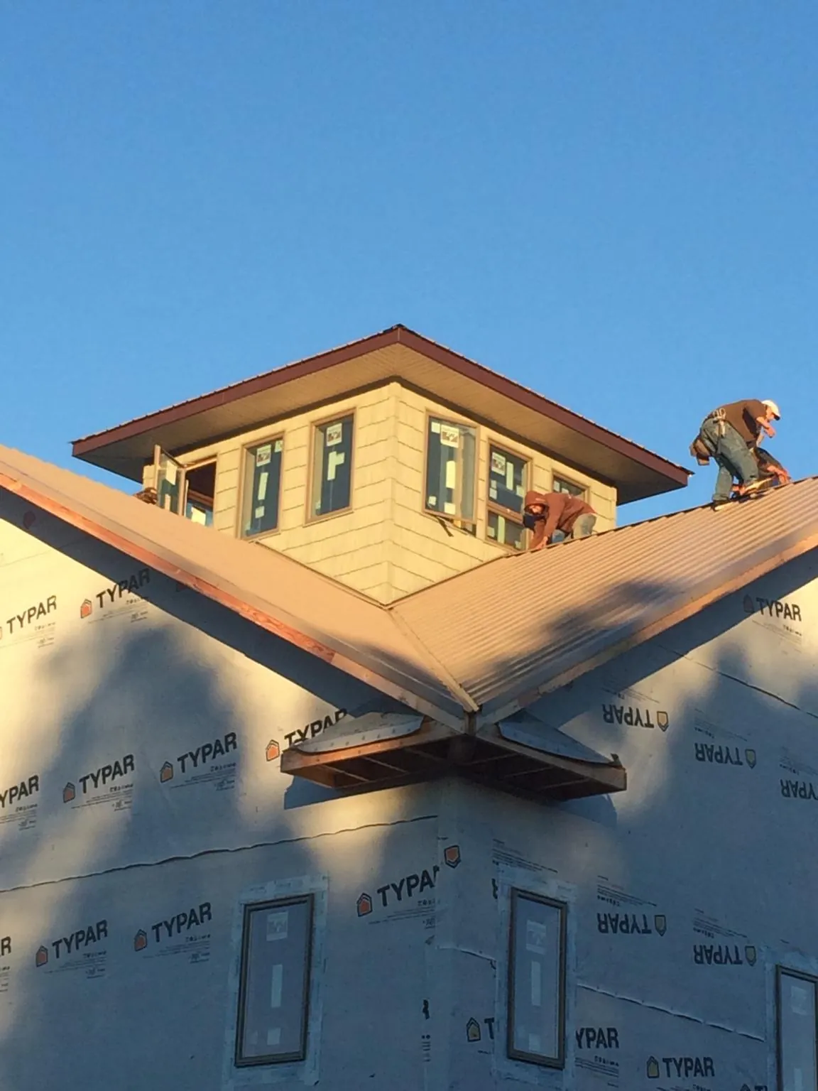 Roofers working around a rooftop cupola on a new metal roof at sunset — Roof Waterproofing in Moosic by Roofing Brothers